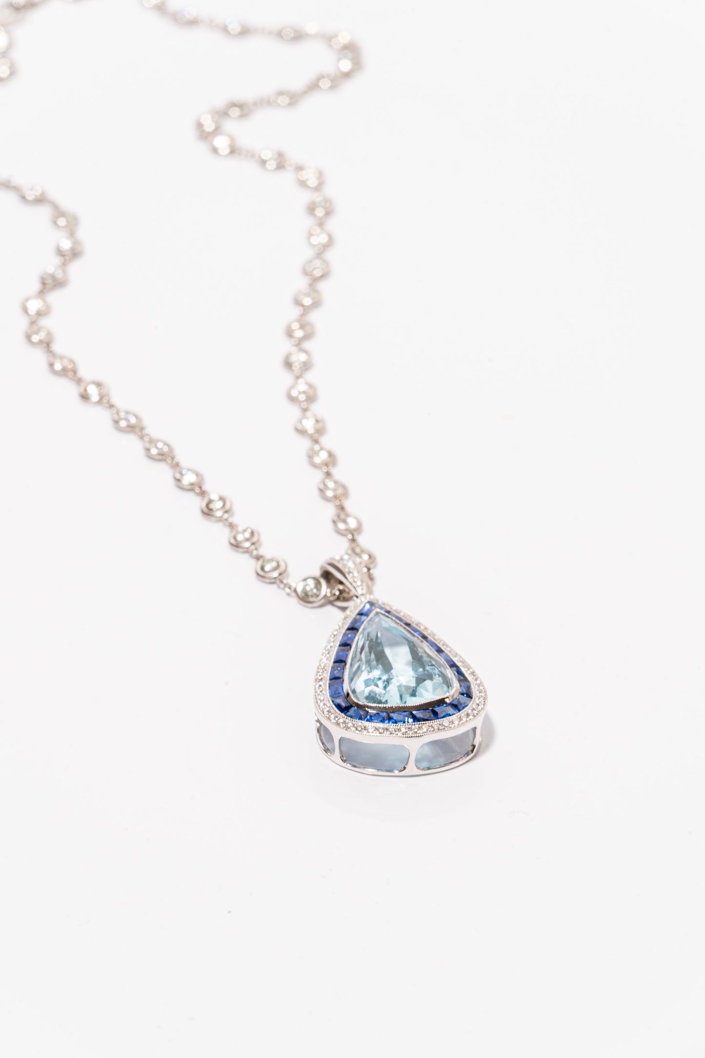 A photo of Pear-Shaped Aquamarine Pendant with sapphires and diamonds on a white gold diamond necklace.