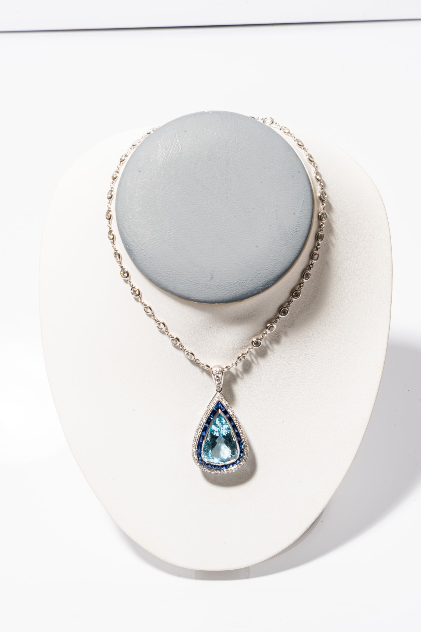 A photo of Pear-Shaped Aquamarine Pendant with sapphires and diamonds on a white gold diamond necklace. 
