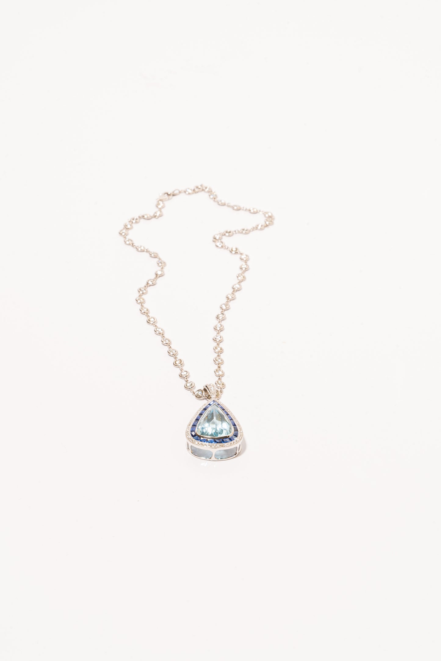 A photo of Pear-Shaped Aquamarine Pendant with sapphires and diamonds on a white gold diamond necklace. 